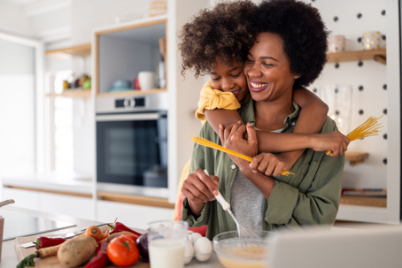 child hugging mother as they cook together